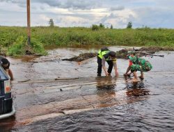 Bersinergi, Bripka Suhanadi Bersama Serda Andri Bahu Membahu Membantu Warga yang Terjebak Banjir di Jalan Potos Ketapang
